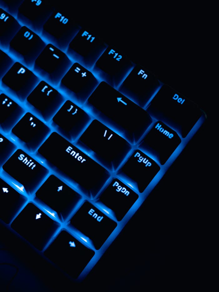 Close-up of a glowing blue keyboard in a dark environment, highlighting keys.