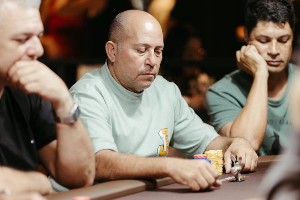 Group of adult men focused on a poker game at a casino table.
