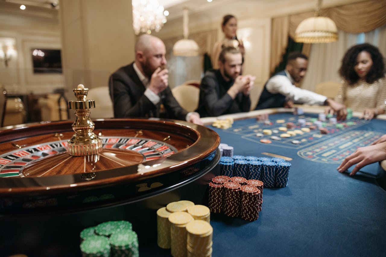 People enjoying a roulette game in an upscale casino setting with chips and a roulette wheel.